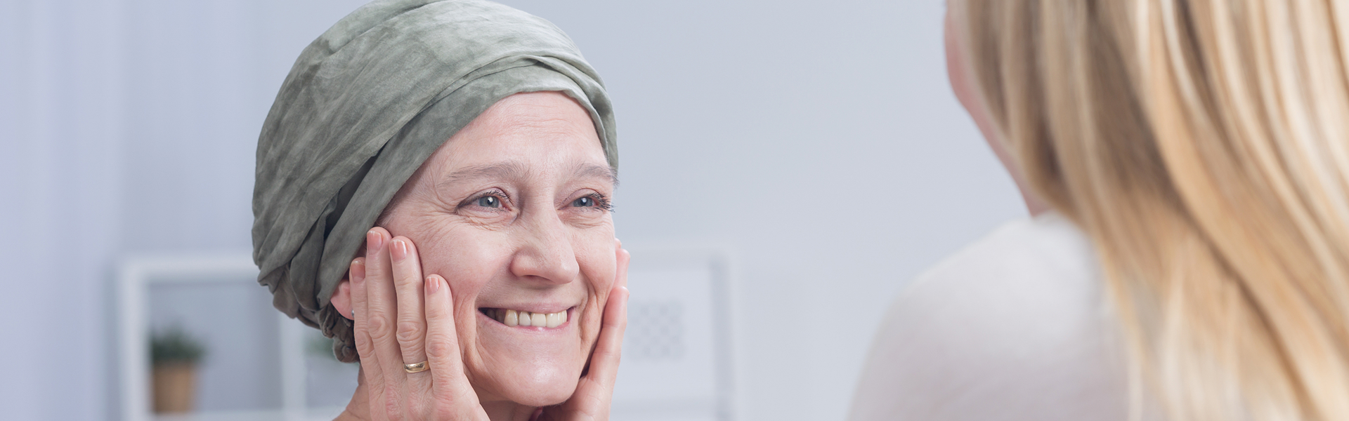 A woman wearing a headscarf is comforted by another woman in a supportive and caring environment.